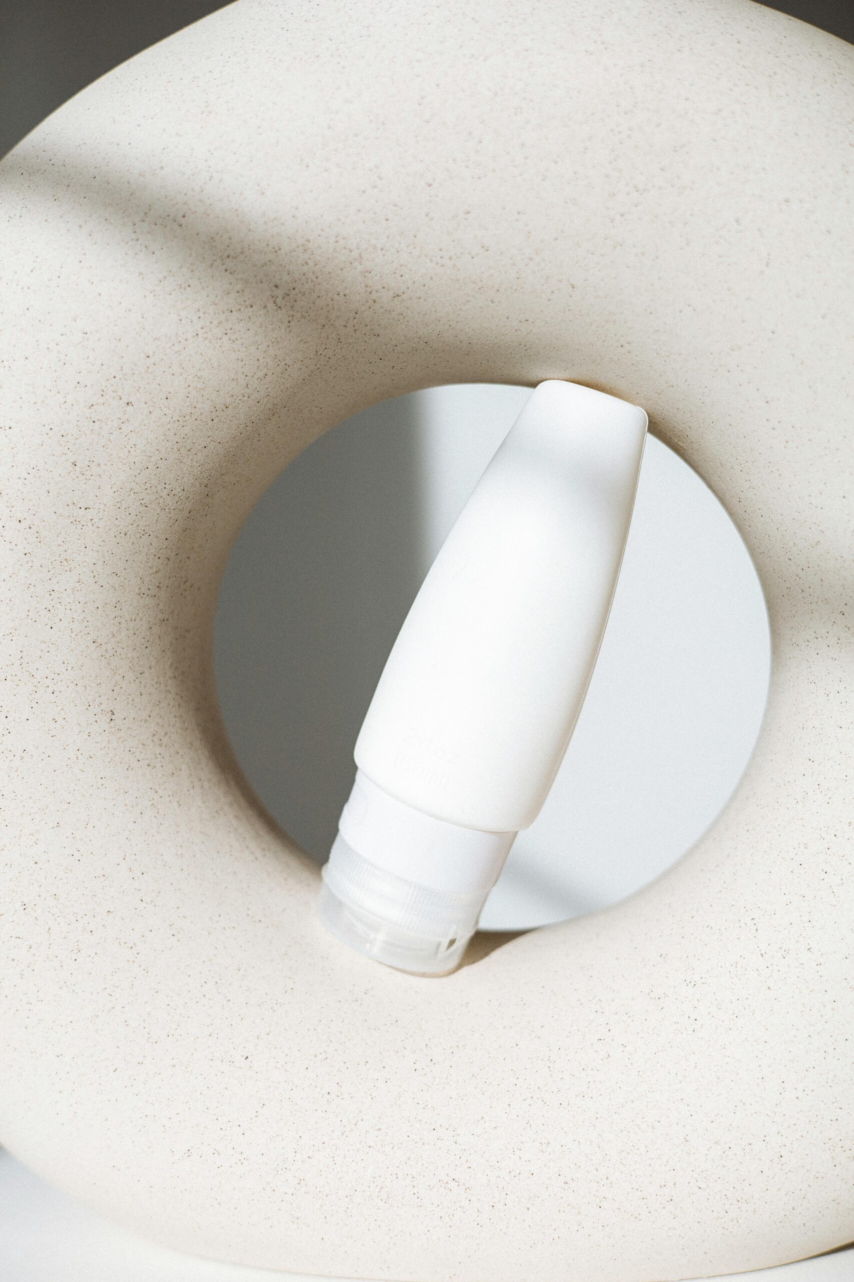 Stylish minimalist still life shot of a cosmetic bottle with creative geometric composition.